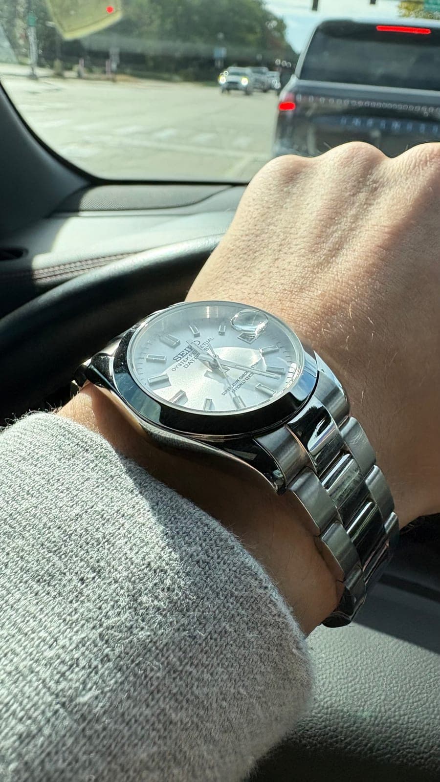 The watch worn on the wrist in daylight, the silver dial catching the sun